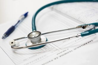 Στατιστικά στοιχεία και ιατρικά εργαλεία σε φόντο που παραπέμπει στο ελληνικό σύστημα υγείας.