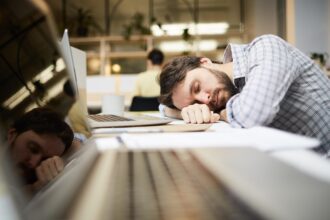 Κουρασμένος άντρας κοιμάται στο γραφείο του μπροστά από τον υπολογιστή