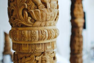 Ξύλινο γλυπτό τέχνης Μάορι σε προθήκη μουσείου με δραματικό φωτισμό