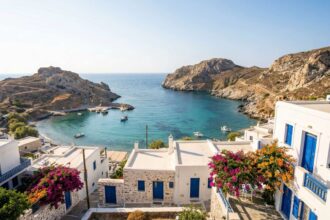 Γραφικός κόλπος με γαλαζοπράσινα νερά, παραδοσιακά λευκά σπίτια και βράχια σε ελληνικό νησί κατά τη διάρκεια του καλοκαιριού