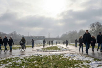 Άνθρωποι περπατούν σε πάρκο της πόλης φορώντας χειμερινά ρούχα ενώ ο πάγος λιώνει στο έδαφος