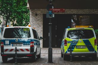 Παλαιό κτίριο υπηρεσιών στη Γερμανία με σημάδια φθοράς και περιπολικά παρκαρισμένα