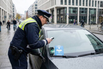 Υπάλληλος δημοτικής αρχής ελέγχει ταμπλό σταθμευμένου αυτοκινήτου για μπλε δίσκο στάθμευσης