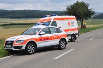 Ασθενοφόρα και οχήματα της πυροσβεστικής με αναμμένους φάρους σε νυχτερινό οδικό δίκτυο μετά από τροχαίο ατύχημα.