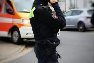 Περιπολικό της γερμανικής αστυνομίας έξω από σχολικό κτίριο στο Eisenach με θολή φιγούρα στο βάθος