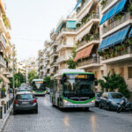 Moderne Elektrobusse fahren durch ein städtisches Wohnviertel in Athen
