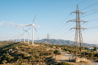Moderne Windräder und Strommasten in Griechenland vor einem blauen Himmel