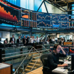 Digitale Anzeigetafeln mit fallenden Kurven an einer internationalen Börse, die den Druck auf die Finanzmärkte symbolisieren