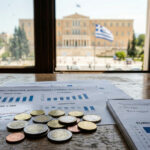 Finanzdokumente und EU-Münzen auf einem Schreibtisch vor dem griechischen Parlament