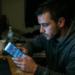 Ein Mann hält ein Smartphone in der Hand und betrachtet eine Webseite für illegales Glücksspiel in Griechenland.