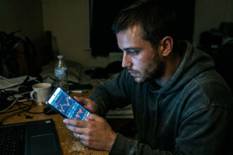 Ein Mann hält ein Smartphone in der Hand und betrachtet eine Webseite für illegales Glücksspiel in Griechenland.