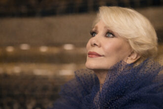 Nahaufnahme der griechischen Sängerin Marinella mit blondem Haar und blauem Tüllkleid, Blick nach oben auf einer Bühne