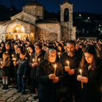 Orthodoxe Gläubige in Griechenland halten brennende Kerzen mit dem Heiligen Licht in der Dunkelheit