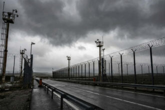Συρματοπλέγματα και κάμερες ασφαλείας σε συνοριακό σταθμό ελέγχου με φόντο έναν συννεφιασμένο ουρανό