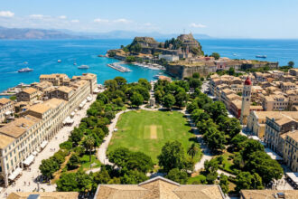 Luftaufnahme des grünen Spianada Platzes in Korfu Stadt mit der alten Festung im Hintergrund.