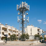 Ein moderner 5G-Sendemast vor blauem Himmel in Griechenland, der den Ausbau der neuen Telekommunikationsinfrastruktur symbolisiert.