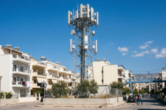 Ein moderner 5G-Sendemast vor blauem Himmel in Griechenland, der den Ausbau der neuen Telekommunikationsinfrastruktur symbolisiert.
