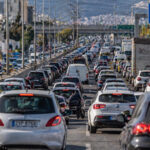 Zahlreiche Fahrzeuge stehen in einem dichten Verkehrsstau auf einer mehrspurigen Straße in Athen, was den alltäglichen Stress der Pendler illustriert.