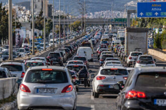Zahlreiche Fahrzeuge stehen in einem dichten Verkehrsstau auf einer mehrspurigen Straße in Athen, was den alltäglichen Stress der Pendler illustriert.