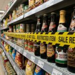 Γυάλινα μπουκάλια μπύρας σε ράφι σούπερ μάρκετ με προειδοποιητική σήμανση ανάκλησης