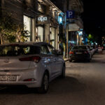 Ein verdunkeltes Auto parkt nachts auf einer schwach beleuchteten Straße in einer griechischen Stadt