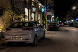 Ein verdunkeltes Auto parkt nachts auf einer schwach beleuchteten Straße in einer griechischen Stadt