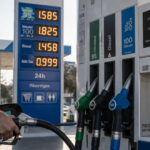 Eine Zapfsäule an einer griechischen Tankstelle zeigt hohe Kraftstoffpreise, während ein Autofahrer tankt.