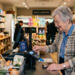 Ηλικιωμένος πελάτης πληρώνει στο ταμείο ενός σύγχρονου γερμανικού σούπερ μάρκετ