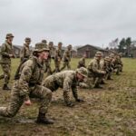 Ομάδα νεαρών νεοσύλλεκτων με στρατιωτικές στολές κατά τη διάρκεια σωματικής άσκησης σε ανοιχτό πεδίο