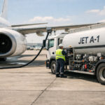 Ein großes Passagierflugzeug wird auf dem Rollfeld eines Flughafens bei Tageslicht mit Kerosin betankt.