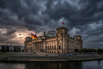 Ο καγκελάριος της Γερμανίας σε αυστηρό ύφος κατά τη διάρκεια πολιτικής ομιλίας μπροστά από τις γερμανικές σημαίες