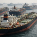 Mehrere große Öltanker und Frachtschiffe liegen dicht beieinander auf offener See vor Anker.