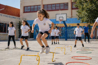 Kinder bei sportlichen Aktivitäten auf einem modernen Schulhof in Griechenland zur Förderung der Gesundheit