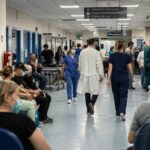 Eine belebte Krankenhauskorridor in Griechenland, medizinisches Personal und wartende Patienten.