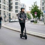 Άνθρωπος οδηγεί ηλεκτρικό πατίνι φορώντας προστατευτικό κράνος σε ευρωπαϊκή πόλη