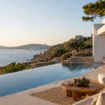 Eine moderne Luxusvilla mit Pool an der griechischen Küste bei Sonnenuntergang.