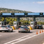 Eine moderne Mautstation auf einer griechischen Autobahn mit Fahrzeugen, die sich den Schranken nähern.