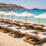Reihen von leeren Sonnenliegen und Schirmen an einem Sandstrand auf der Insel Mykonos
