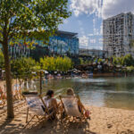 Τεχνητή παραλία με άμμο και μικρά σκάφη σε λίμνη δίπλα σε αστικό περιβάλλον