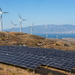 Moderne Windkraftanlagen und großflächige Solarparks in der sonnigen griechischen Landschaft.