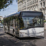 Ein moderner städtischer Bus fährt durch eine griechische Metropole, unmarkiert, bereit für ein neues Design.