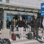 Viele Touristen mit Koffern am griechischen Flughafen an einem sonnigen Wintertag.