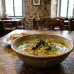 Eine Schüssel mit traditioneller griechischer Magiritsa-Suppe mit frischen Kräutern in einer Athener Taverne