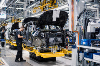 Εργαζόμενοι σε γραμμή παραγωγής αυτοκινήτων σε βιομηχανική εγκατάσταση