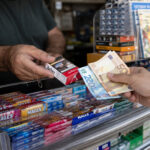 Eine Hand bezahlt eine Schachtel Zigaretten mit Euro-Scheinen an einem Kiosk in Griechenland