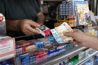 Eine Hand bezahlt eine Schachtel Zigaretten mit Euro-Scheinen an einem Kiosk in Griechenland