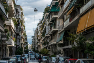 Eine typische dicht bebaute Straße in Athen mit mehrstöckigen Mehrfamilienhäusern aus Beton und vielen Balkonen.