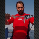 Griechischer Fischer zeigt einen von Hasenkopfkugelfischen teilweise gefressenen Fisch auf einem Boot in Griechenland.