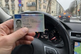 Ένας οδηγός στη Γερμανία κρατάει στα χέρια του το νέο ευρωπαϊκό δίπλωμα οδήγησης μέσα στο αυτοκίνητο