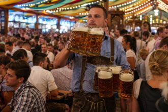 Σερβιτόρος του Oktoberfest στο Μόναχο κρατάει πολλά ποτήρια μπίρας ανάμεσα στο πλήθος.